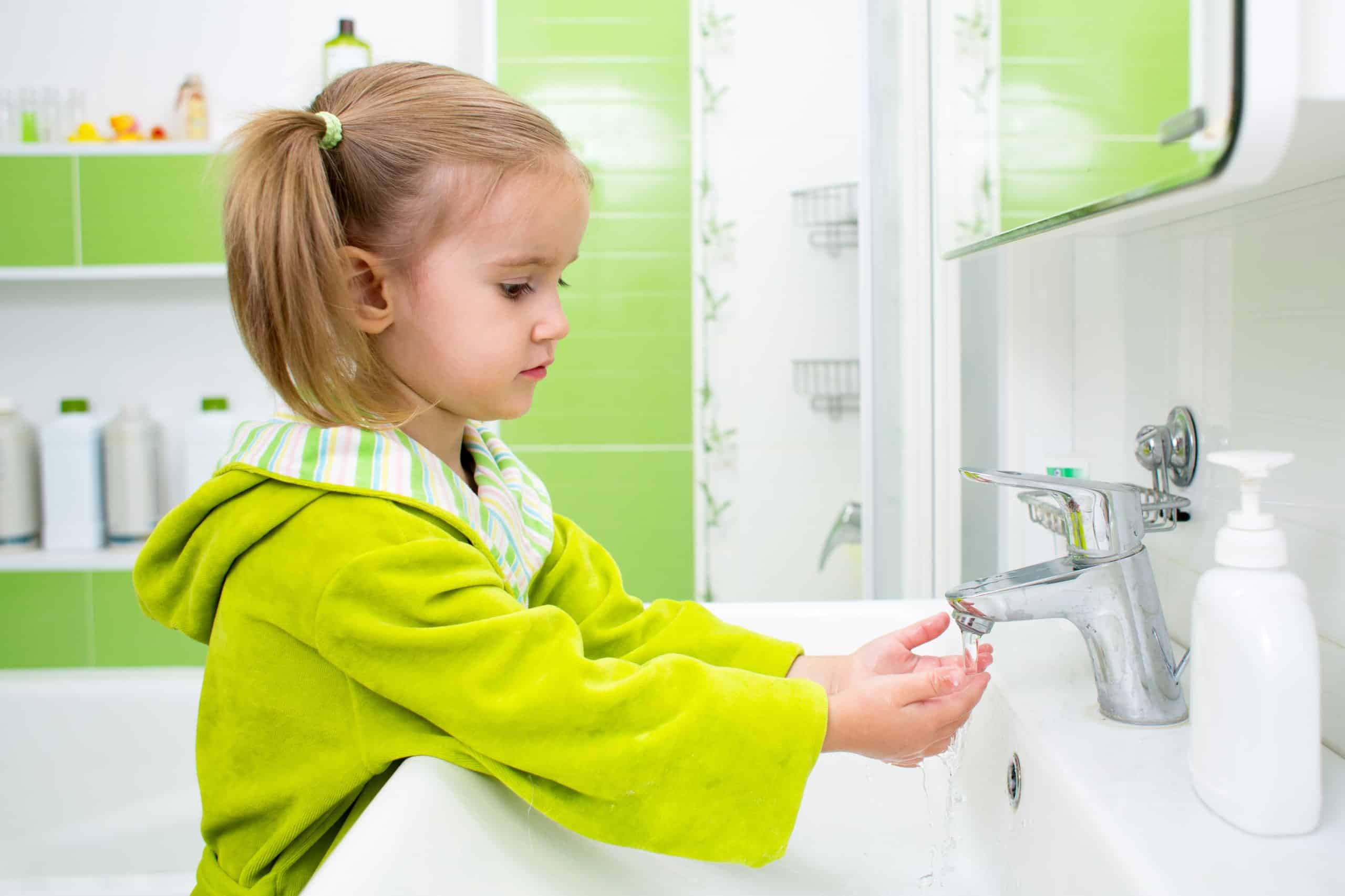 Cute little girl washing face and hands in bathroom